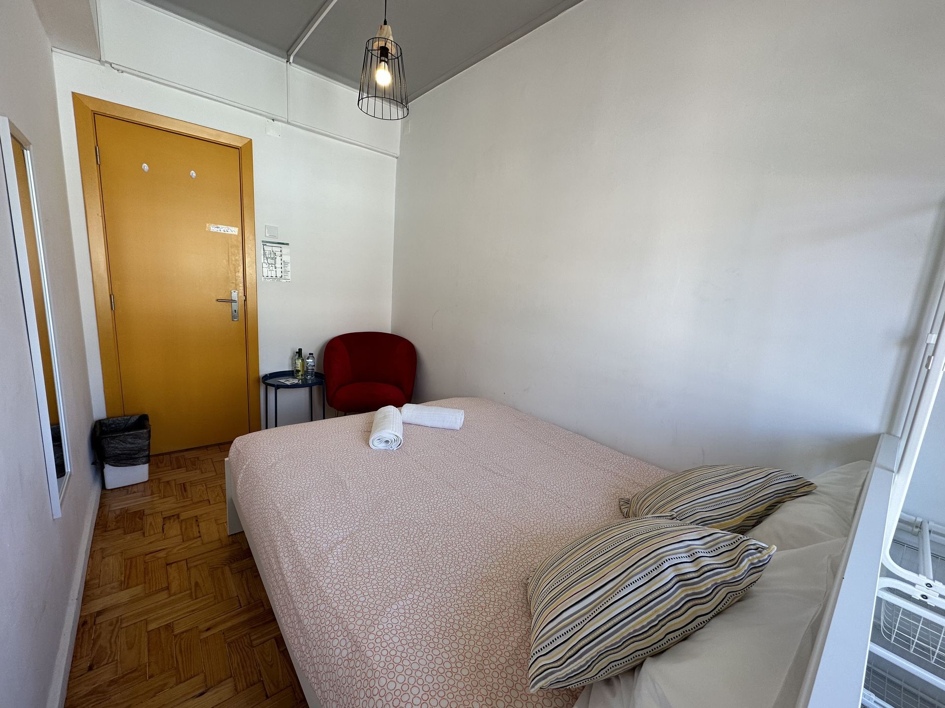 A bedroom with a bed , chair , table and mirror.