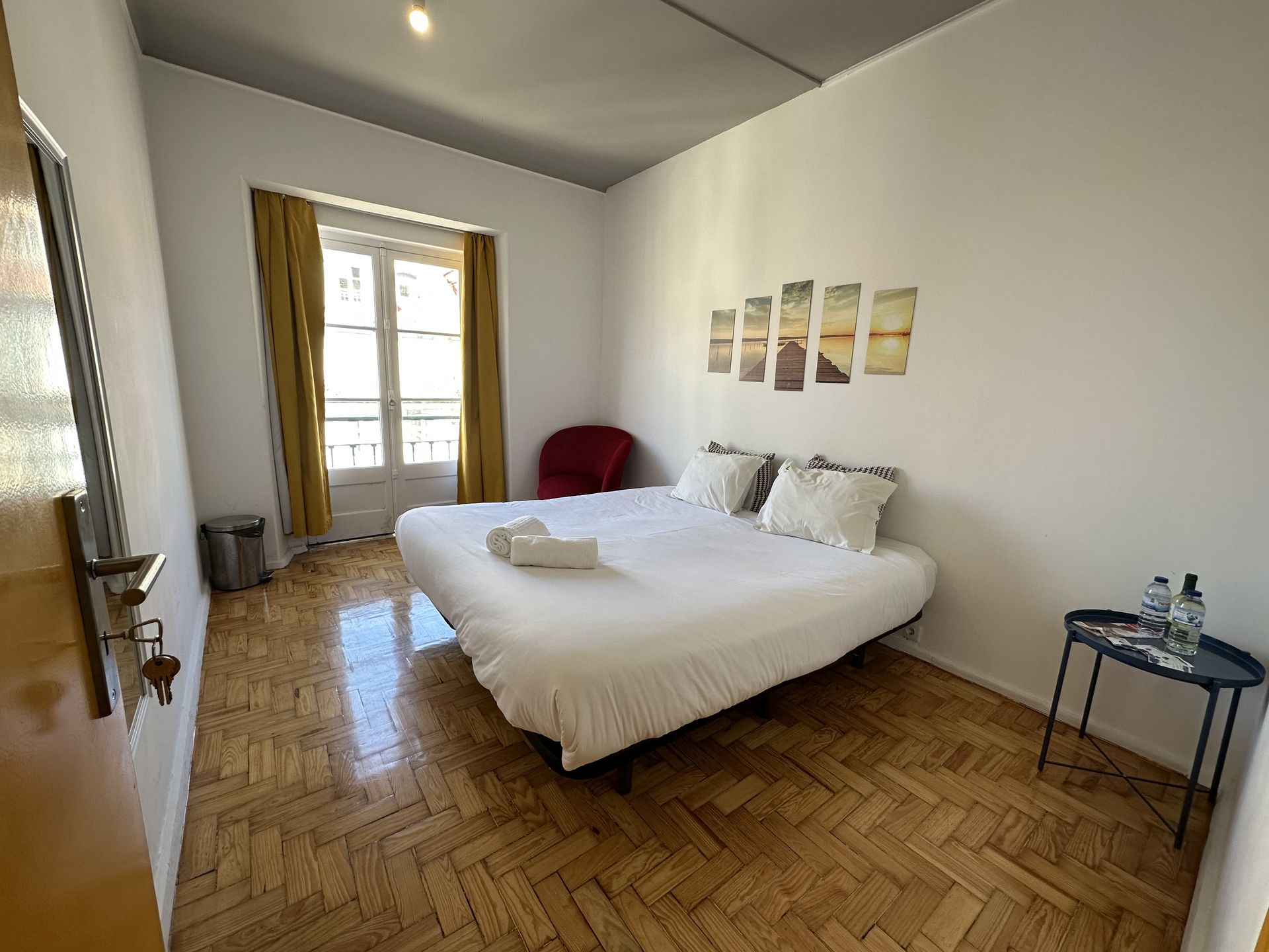 A bedroom with a bed , chair , table and window.