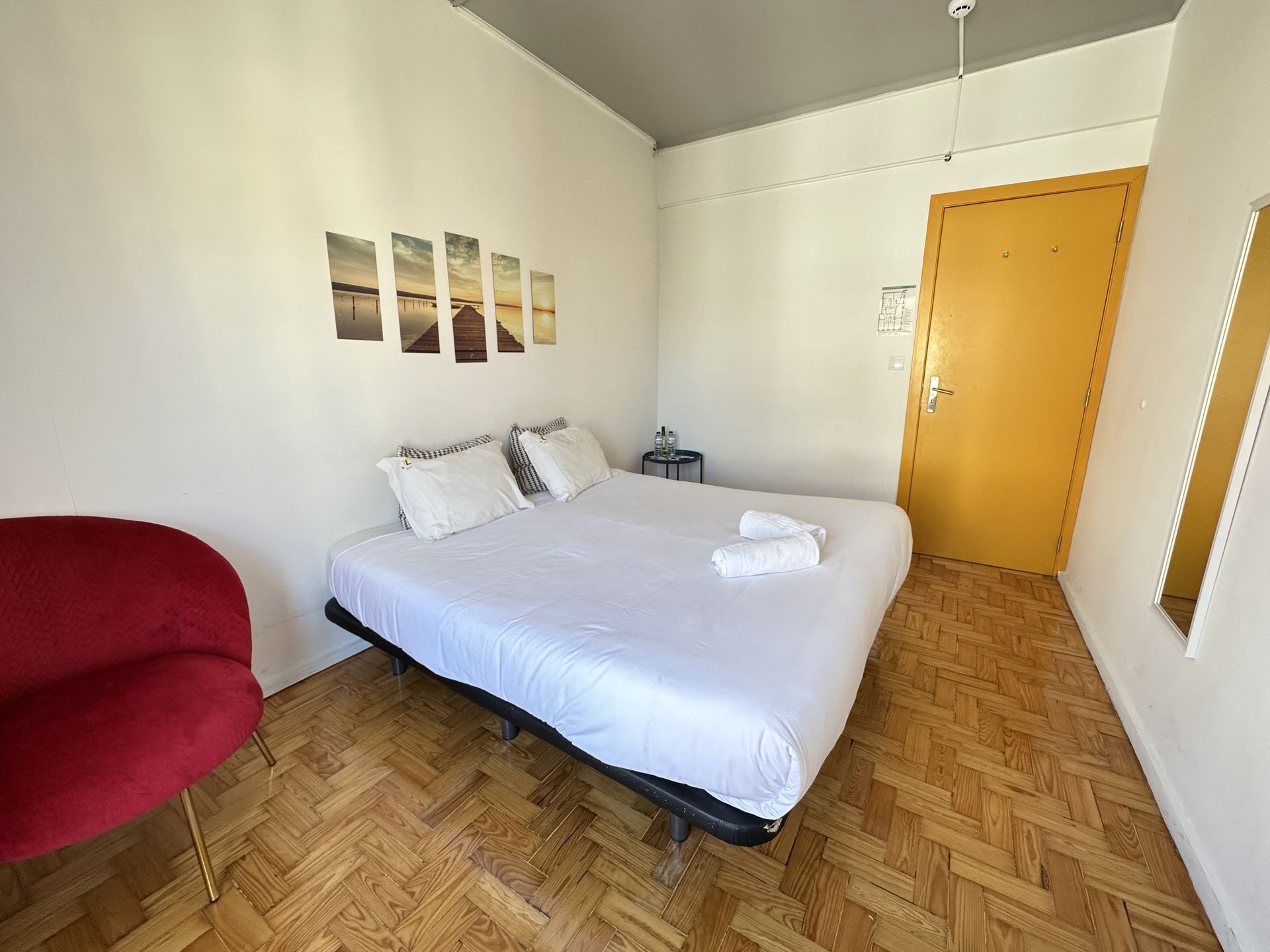 A bedroom with a bed , chair and mirror.