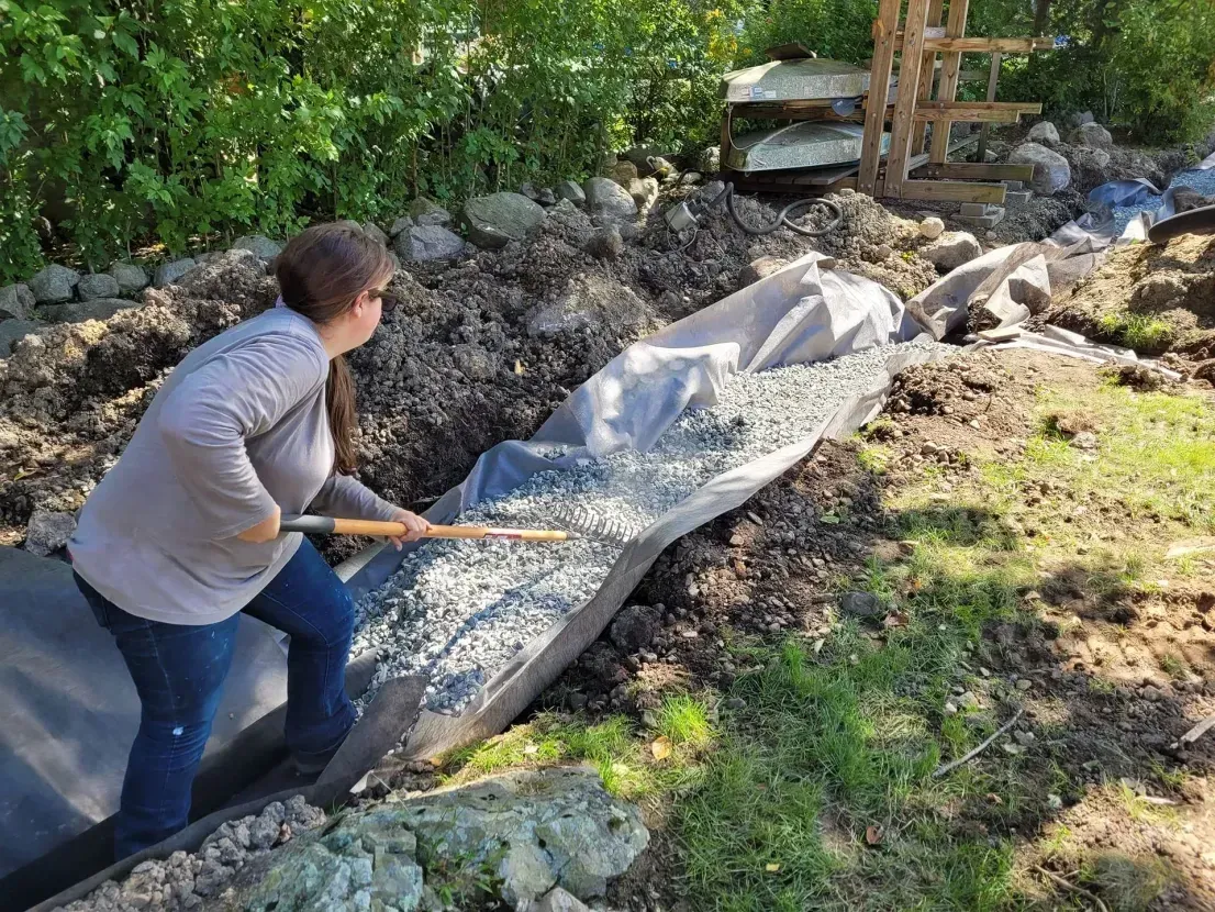 A woman is digging in the dirt with a shovel.