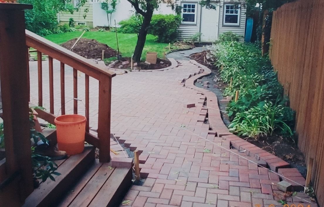 A large brick house with a concrete walkway leading to it.