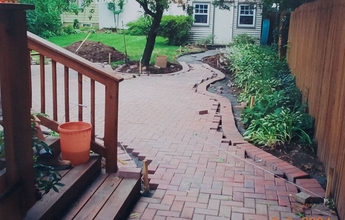 A brick walkway is being built in a backyard