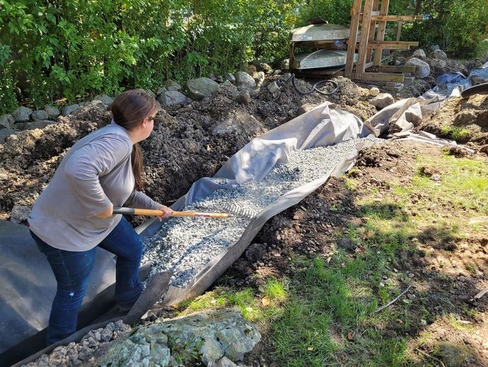 A woman is digging in the dirt with a shovel.