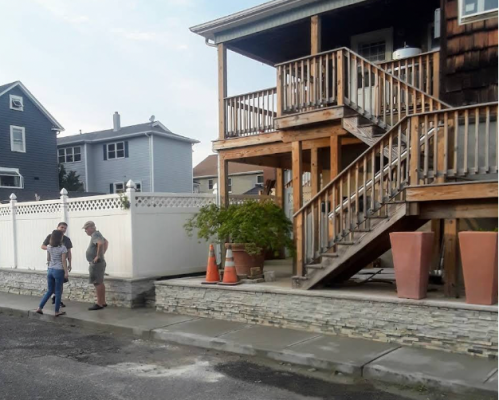 A group of people standing outside of a house with stairs