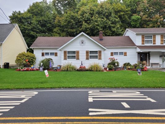 A white house sits on the corner of a street