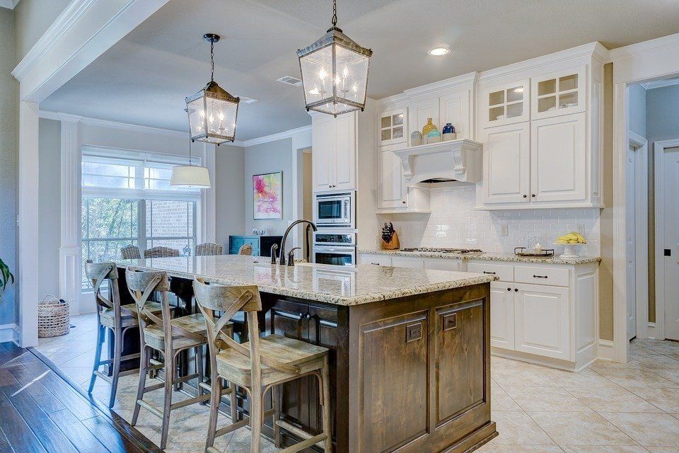 a kitchen with white cabinets , granite counter tops , and a large island .