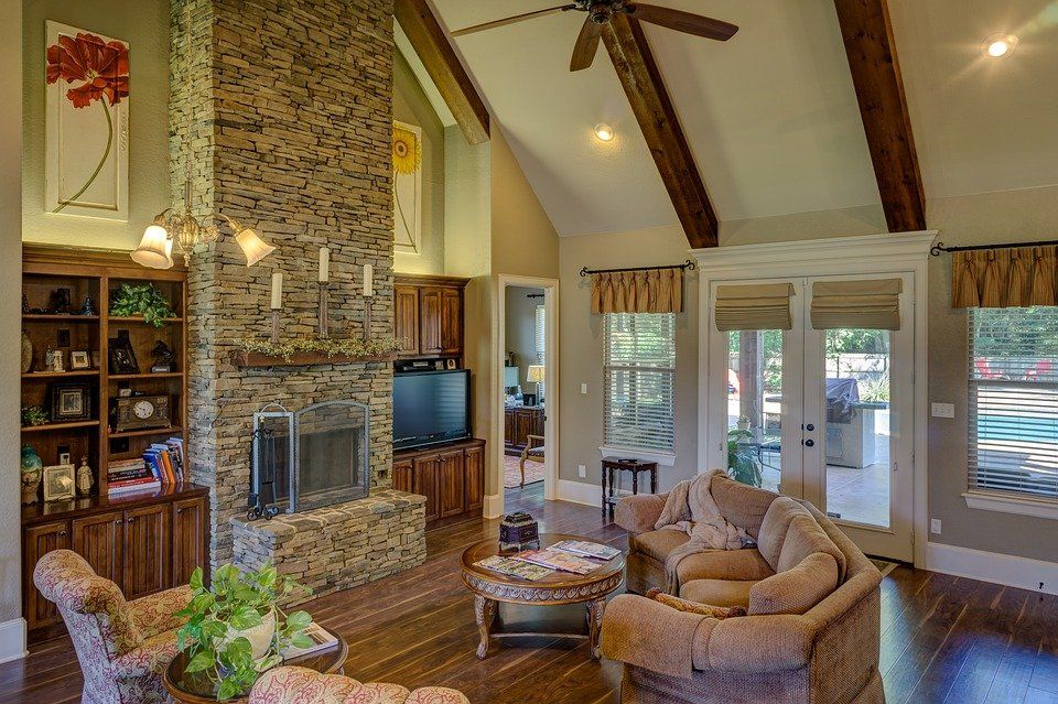 a living room with a stone fireplace and a ceiling fan .