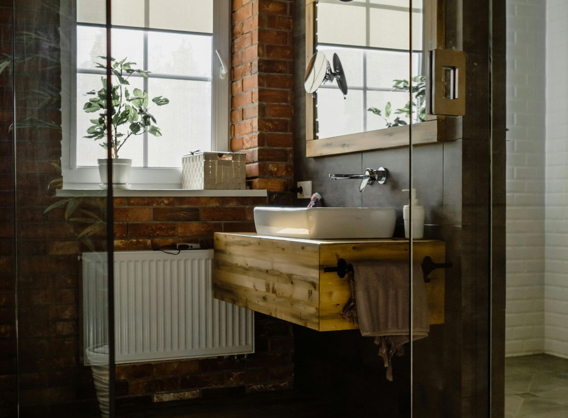 Bathroom with brick wall, wooden vanity, and large window.