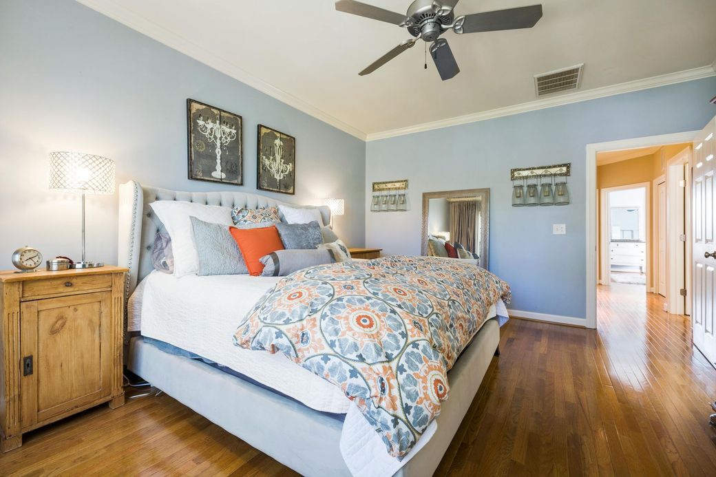 Bedroom with a bed, nightstand, and chandelier artwork; blue walls, hardwood floor.