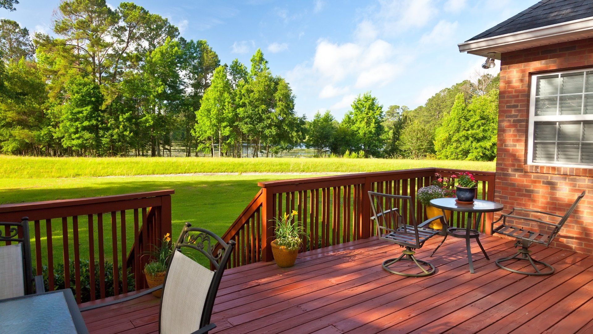 Backyard deck overlooking a large backyard.  The deck is stained a reddish colour and is attached to the house.