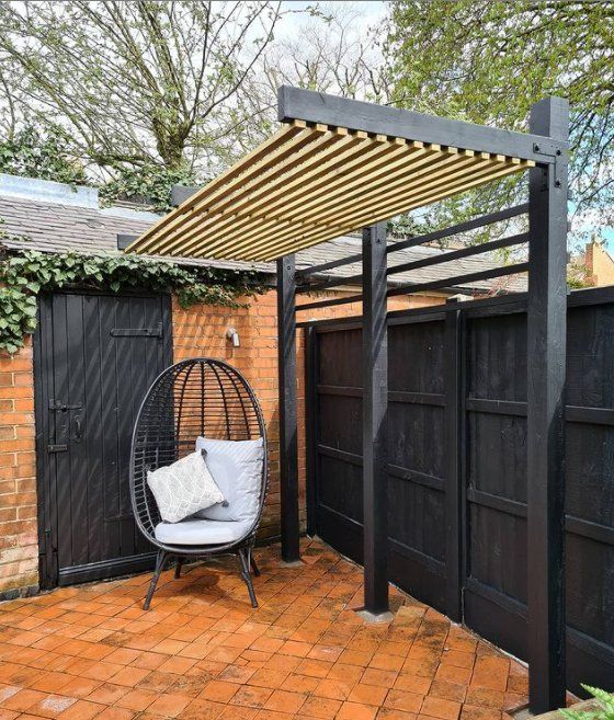 Backyard patio with a black fence and a small pergola.