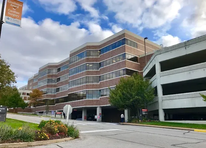 Multi-story brick building with curved edges and a parking garage, on a cloudy day.