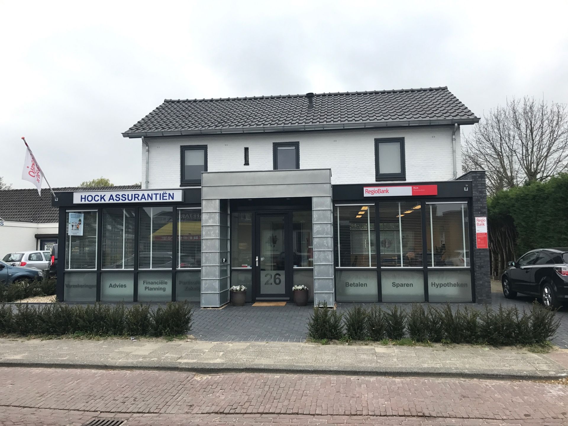 Een wit gebouw met een bordje met de tekst 'hoge assurance' erop