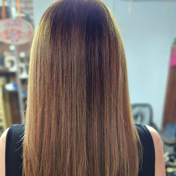 Cabello largo, liso y castaño, mostrando la espalda de una persona, posiblemente en un salón.