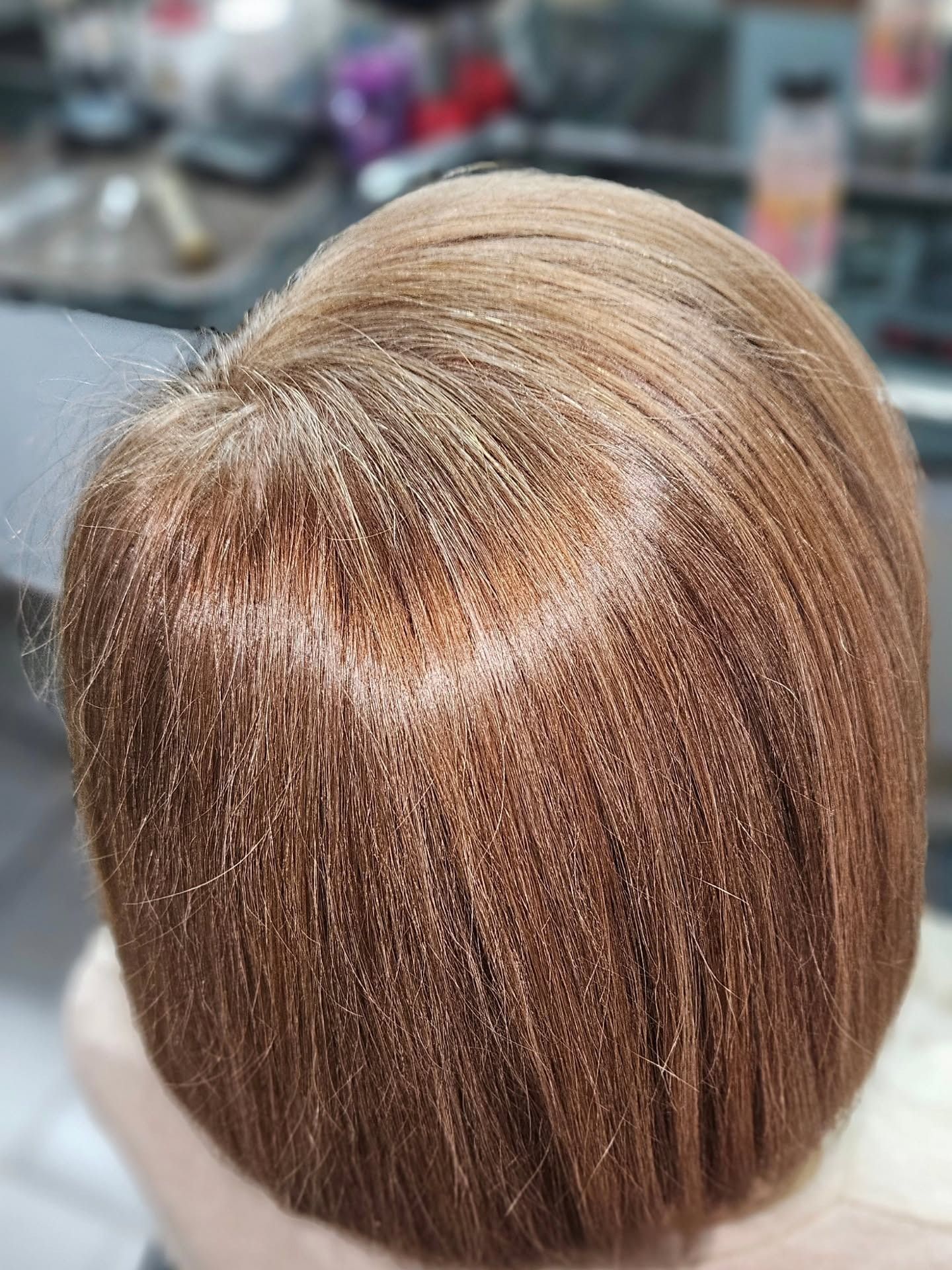 Primer plano de cabello castaño, probablemente recién peinado con un corte bob, en un salón de belleza.