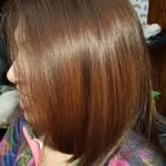 Mujer con cabello castaño, corte bob en ángulo, iluminada de lado.