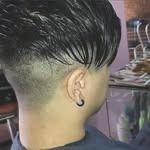 Persona con corte de pelo descolorido y pendiente negro.