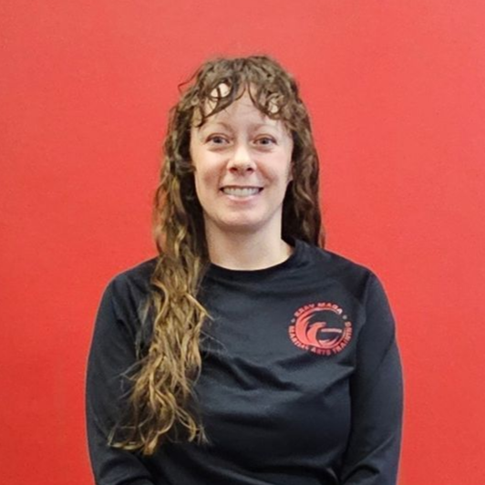 Woman standing, smiling. Wearing a black top