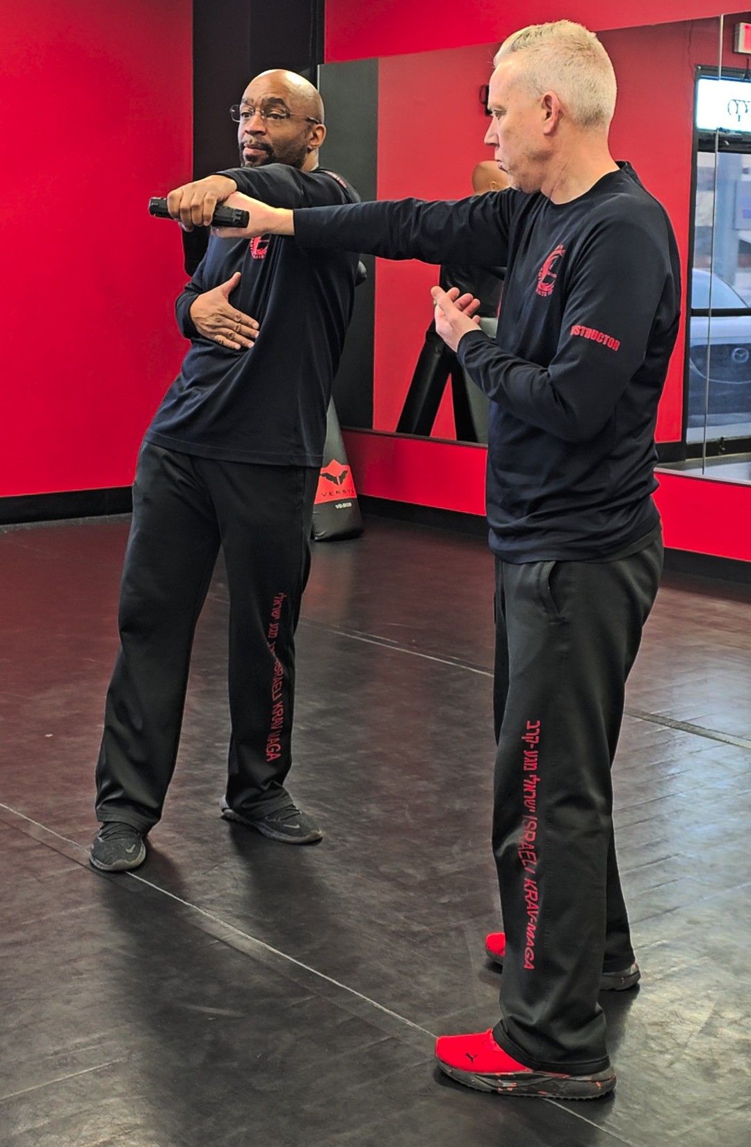 Two men are practicing martial arts in a gym.