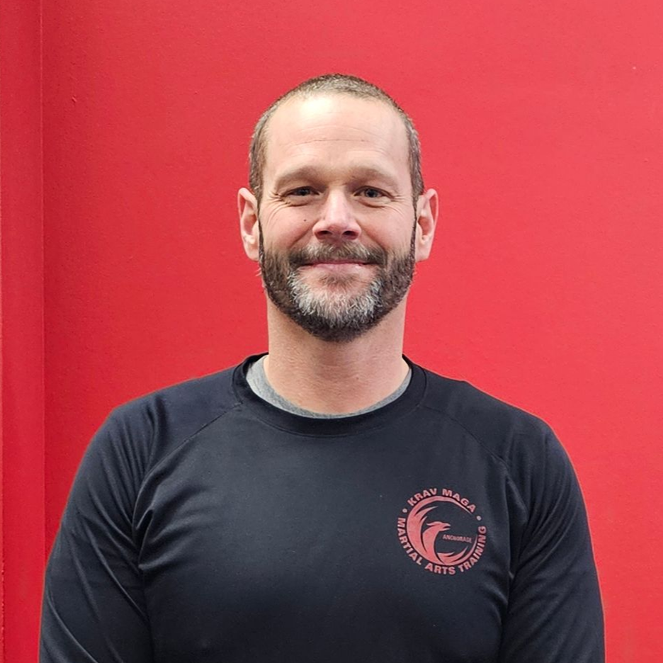 Man standing, smiling. Wearing a black top