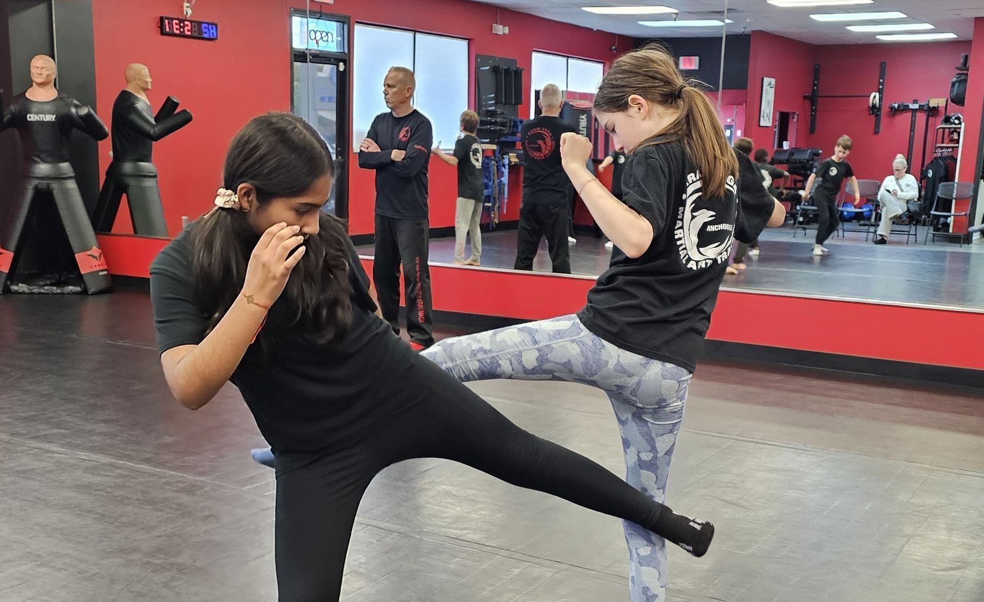 Two girls are kicking each other at a martial studio