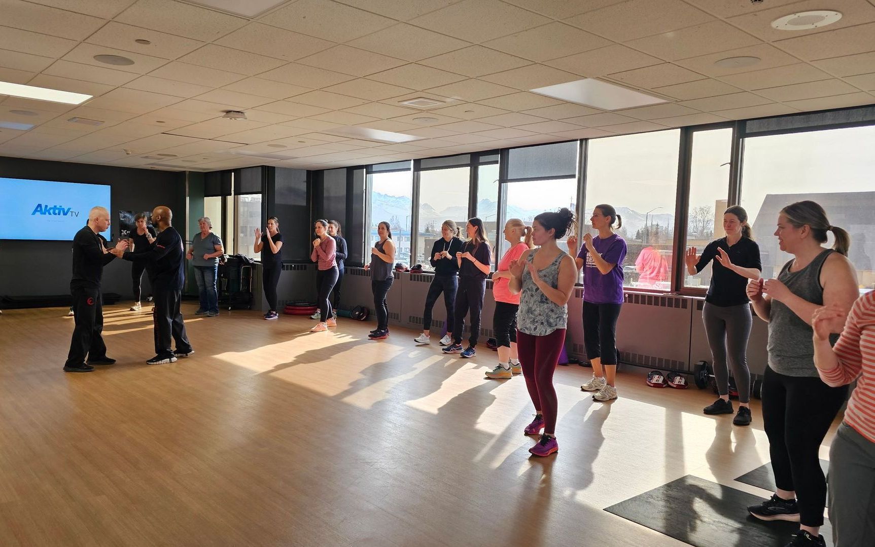 A group of business people are standing in a hallway talking to each other.