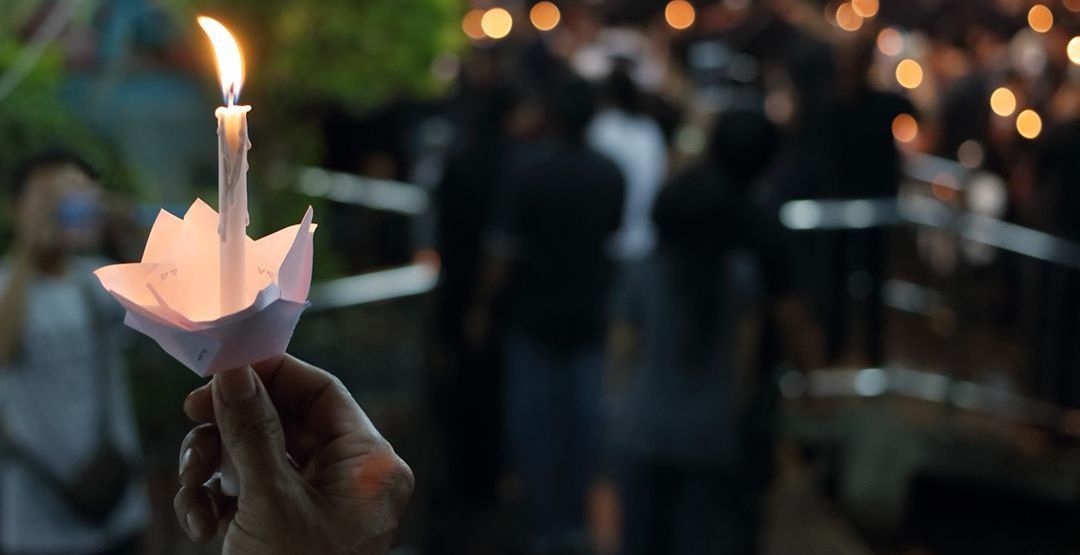 a person is holding a lit candle in front of a crowd .
