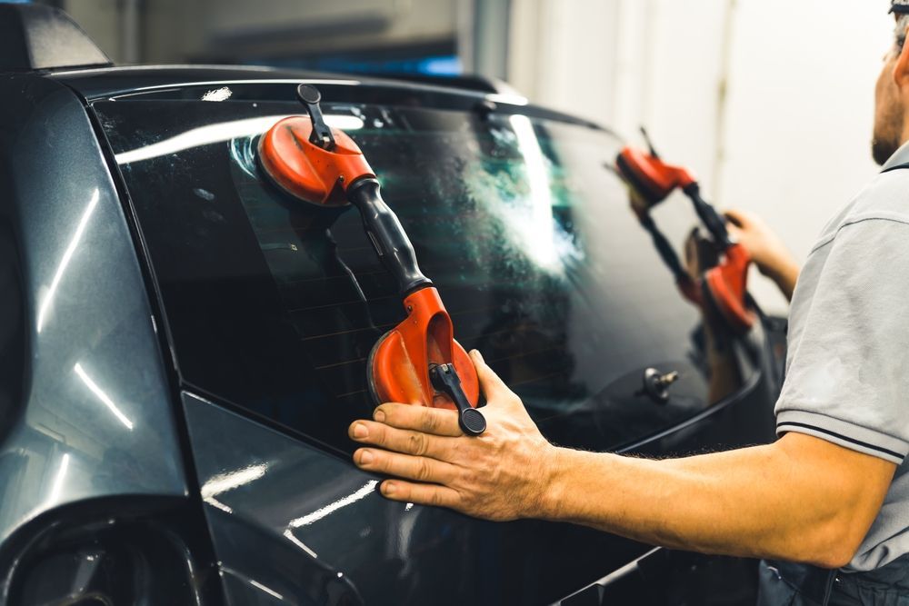 A person using red suction cups to remove a car window.