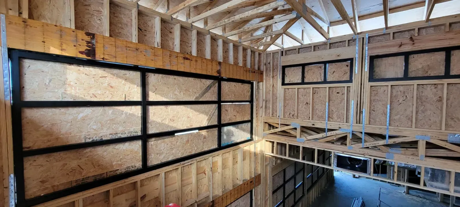 Interior of a building under construction, showing a large glass window and framing.