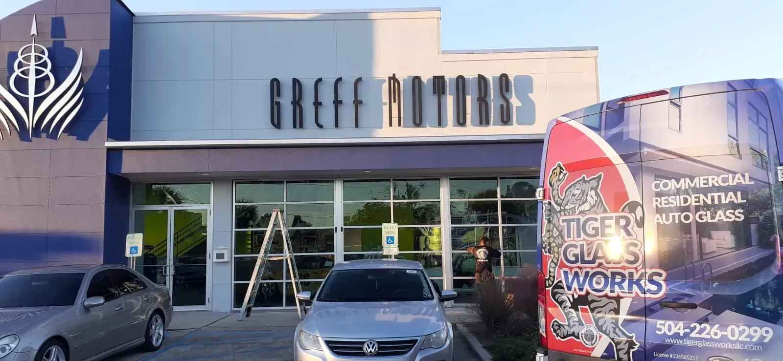 Exterior of Greeff Motors building with a Tiger Glass Works vehicle parked nearby.