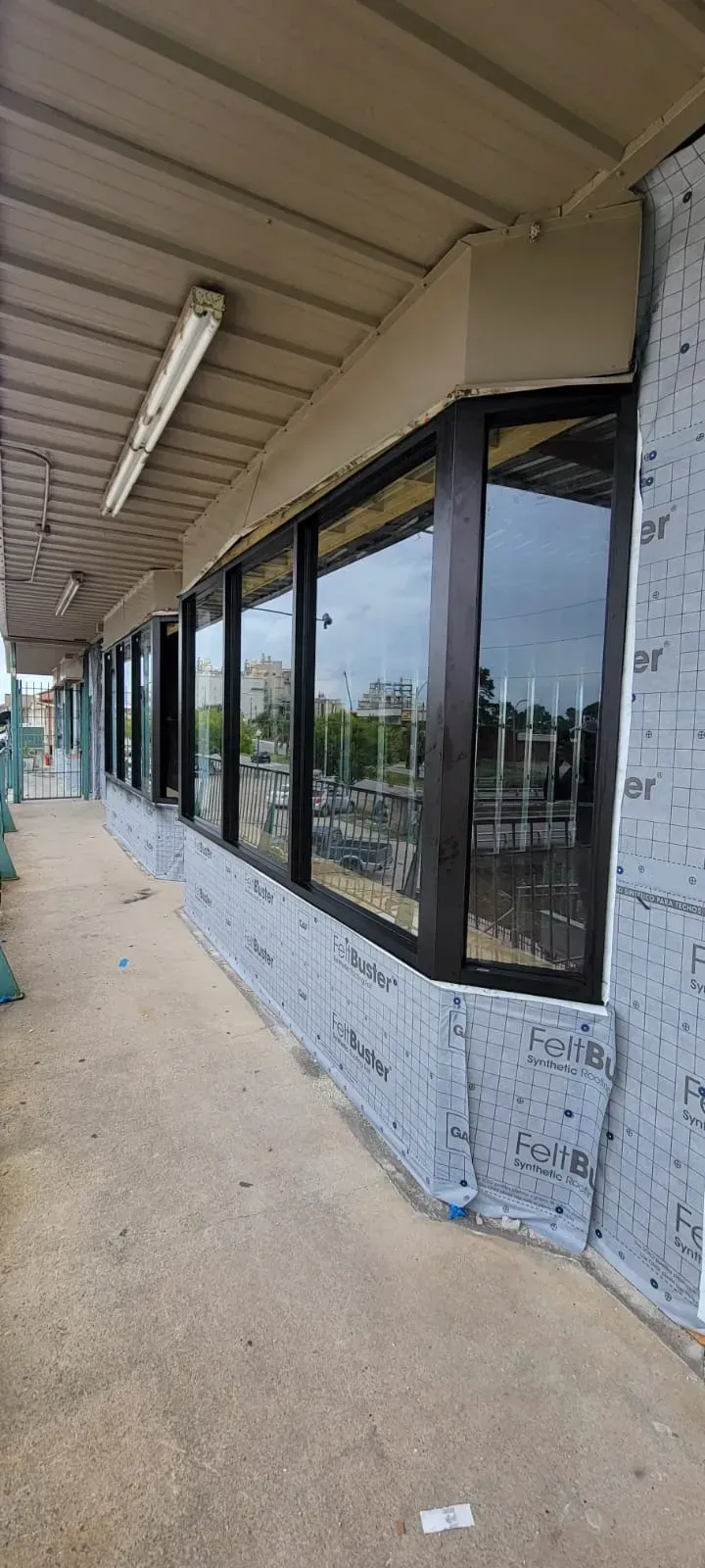 Building exterior with large windows, covered walkway, and gray textured facade.