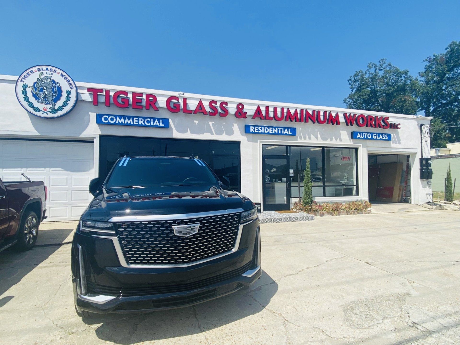 Black SUV parked in front of Tiger Glass & Aluminum Works, a building with a business sign.
