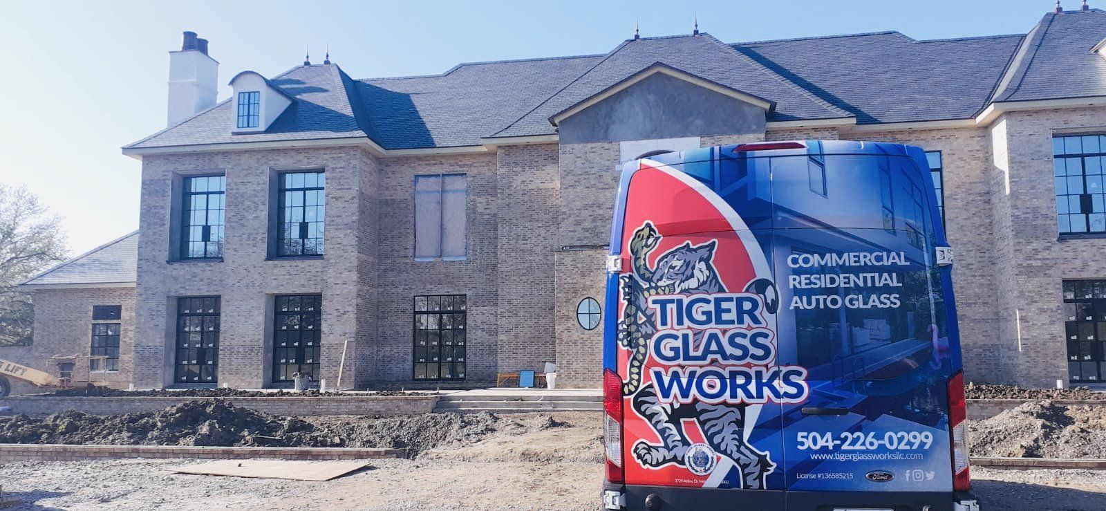 A Tiger Glass Works van parked in front of a brick house.
