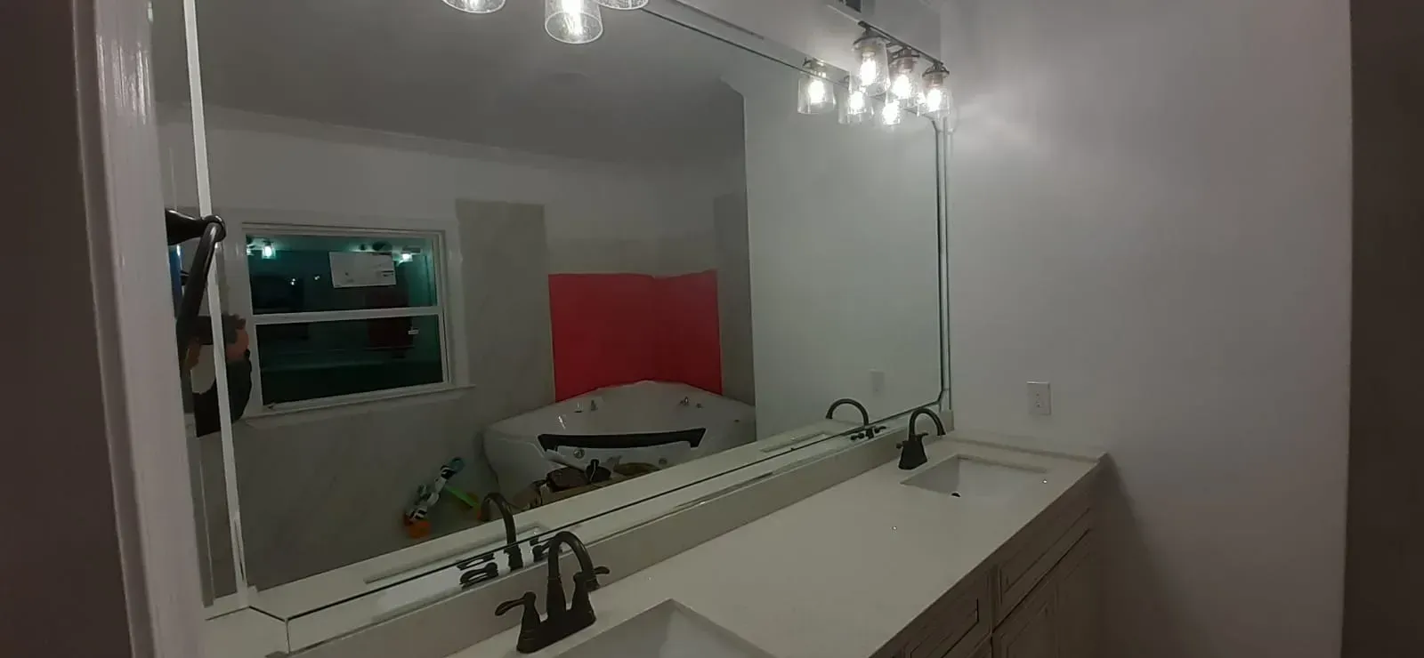 Bathroom with a large mirror, vanity, and lighting fixture.