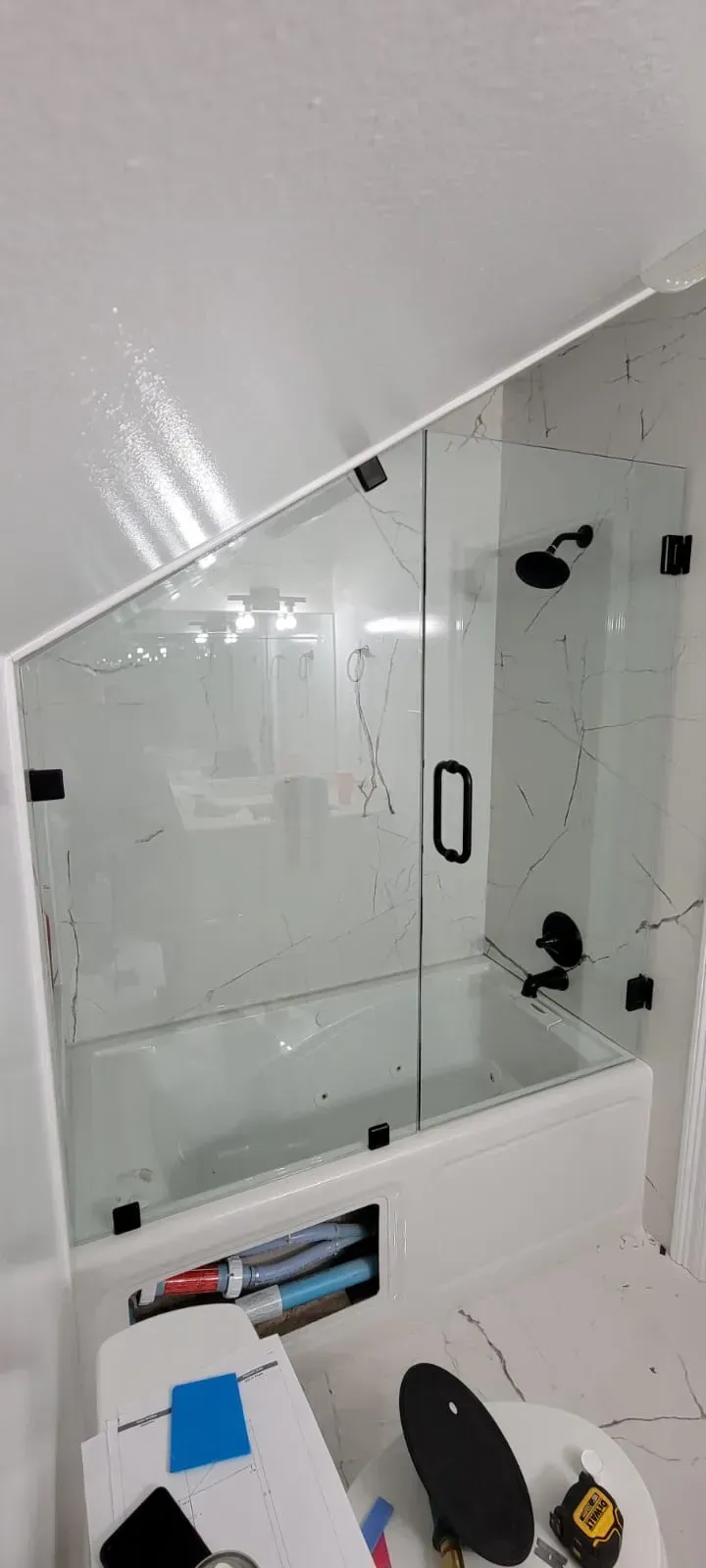 Bathroom with glass shower doors and black fixtures; partially constructed.