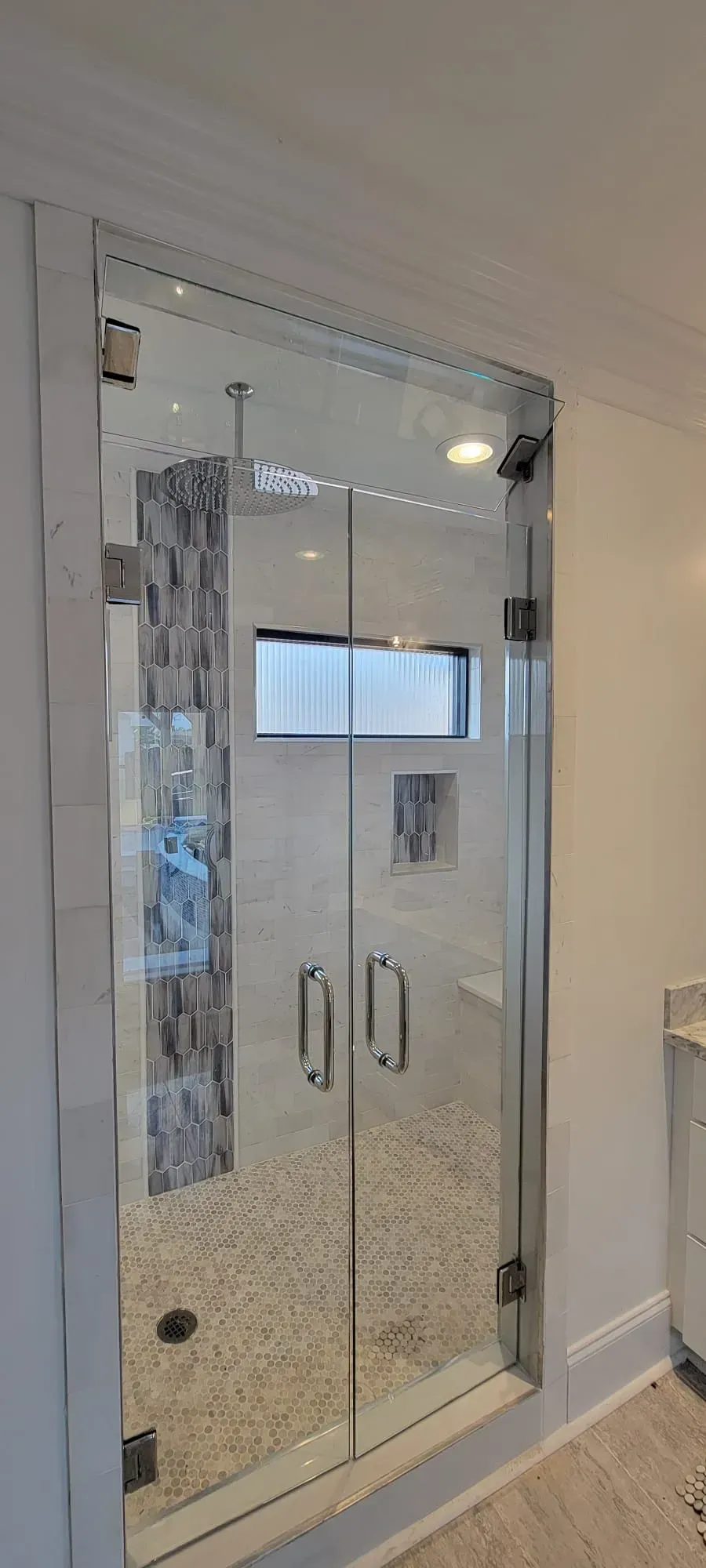 Glass shower enclosure with double doors and decorative tile interior.