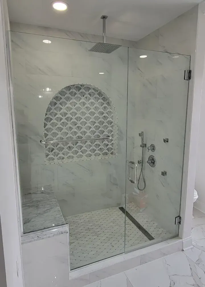 Modern glass shower with patterned tile niche, bench, and rain shower head.
