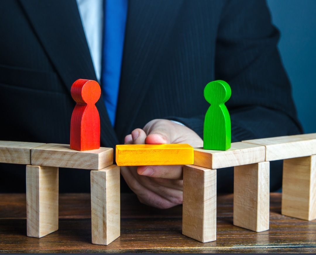 A man in a suit and tie is holding a bridge made of wooden blocks.