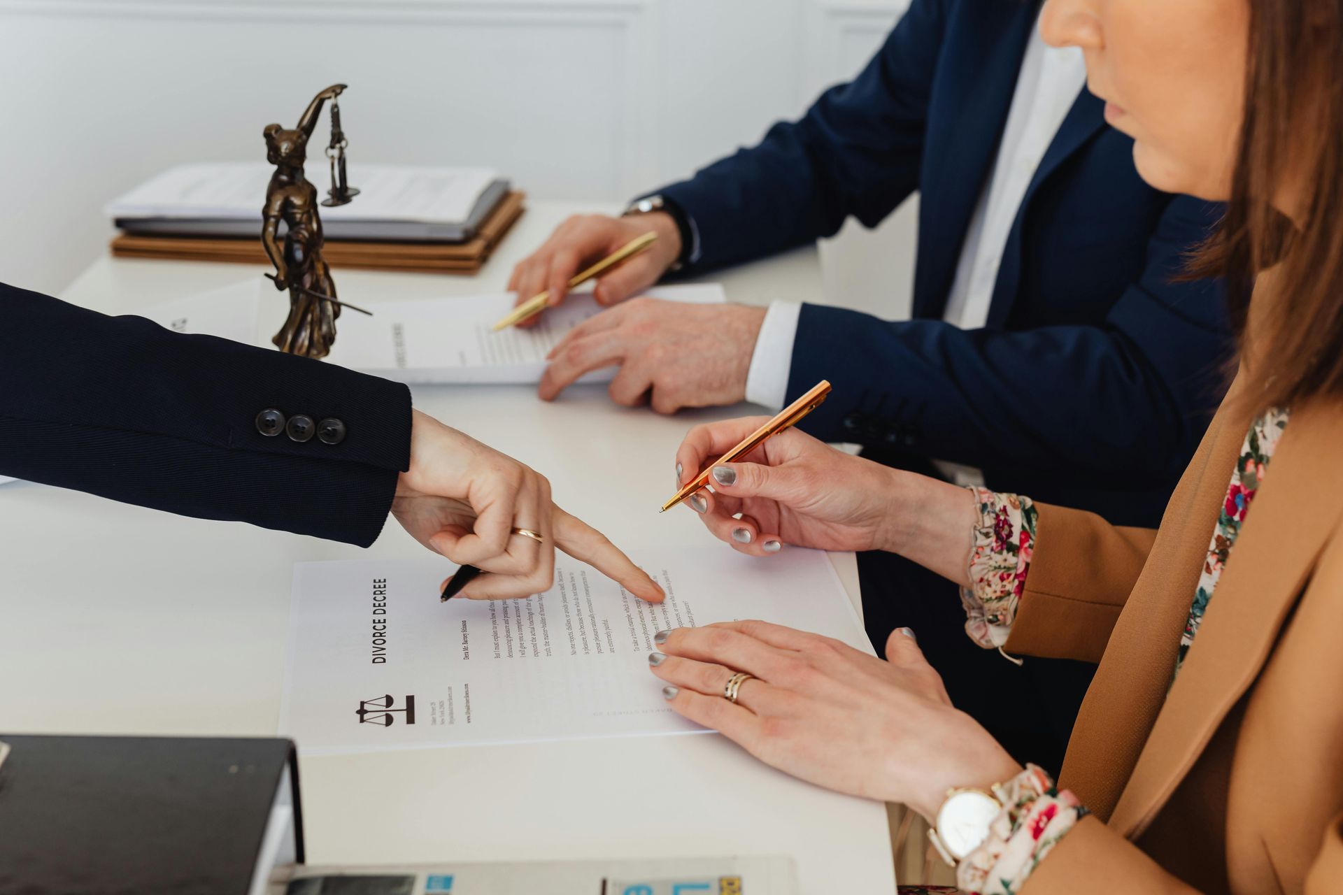 A group of people are sitting at a table signing a document for divorce mediation