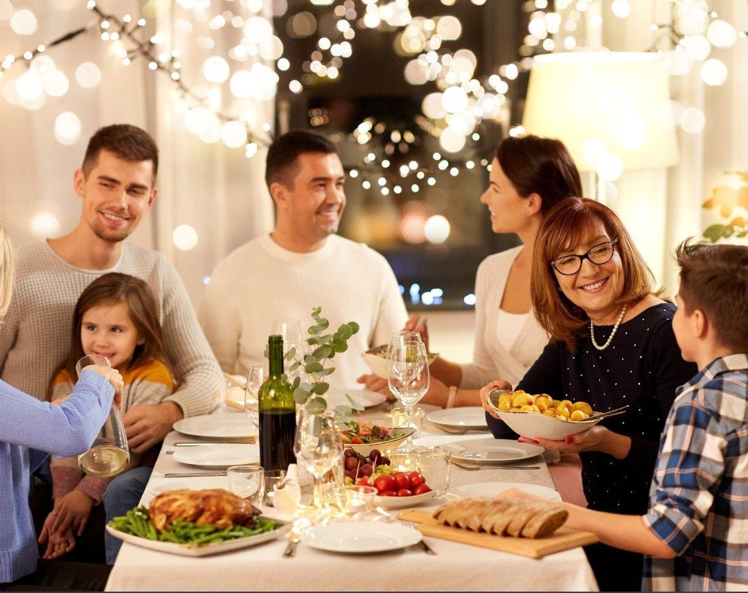 A large family is sitting at a table eating christmas dinner.