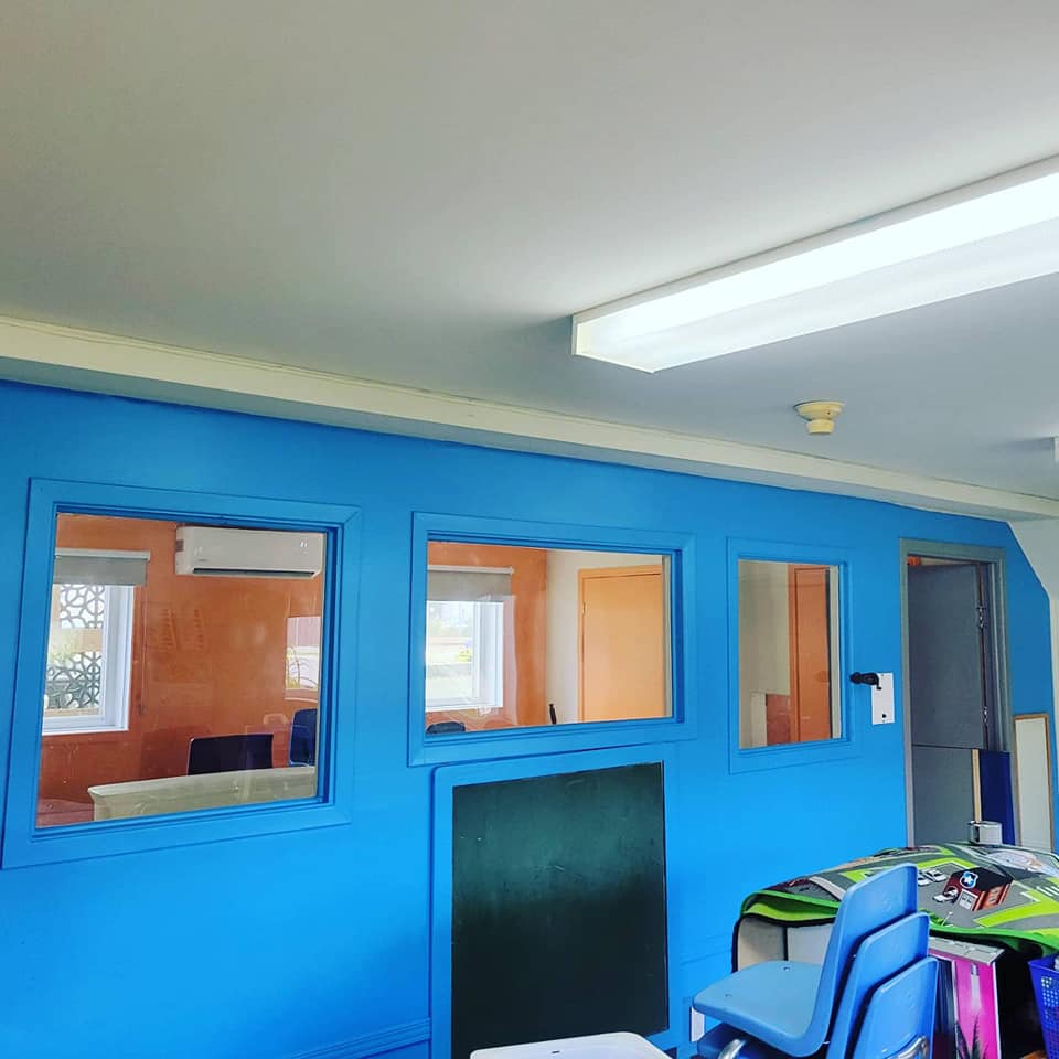 Une pièce avec des murs bleus et quelques fenêtres