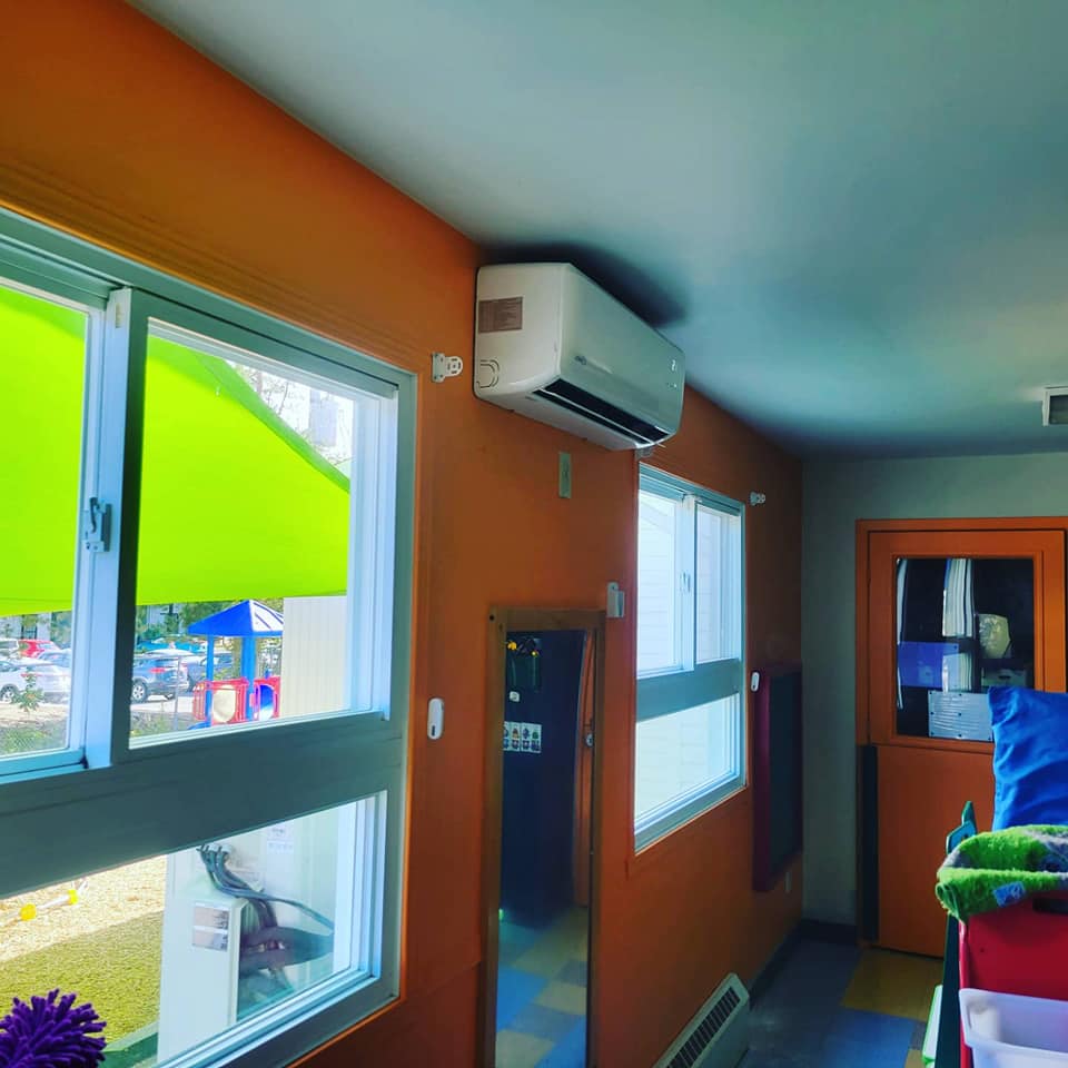 Une pièce avec beaucoup de fenêtres et un climatiseur suspendu au plafond