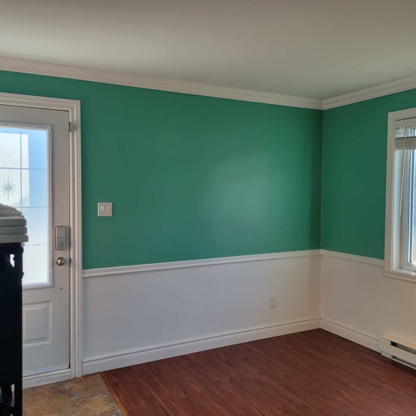 Une pièce vide avec des murs verts et des garnitures blanches.