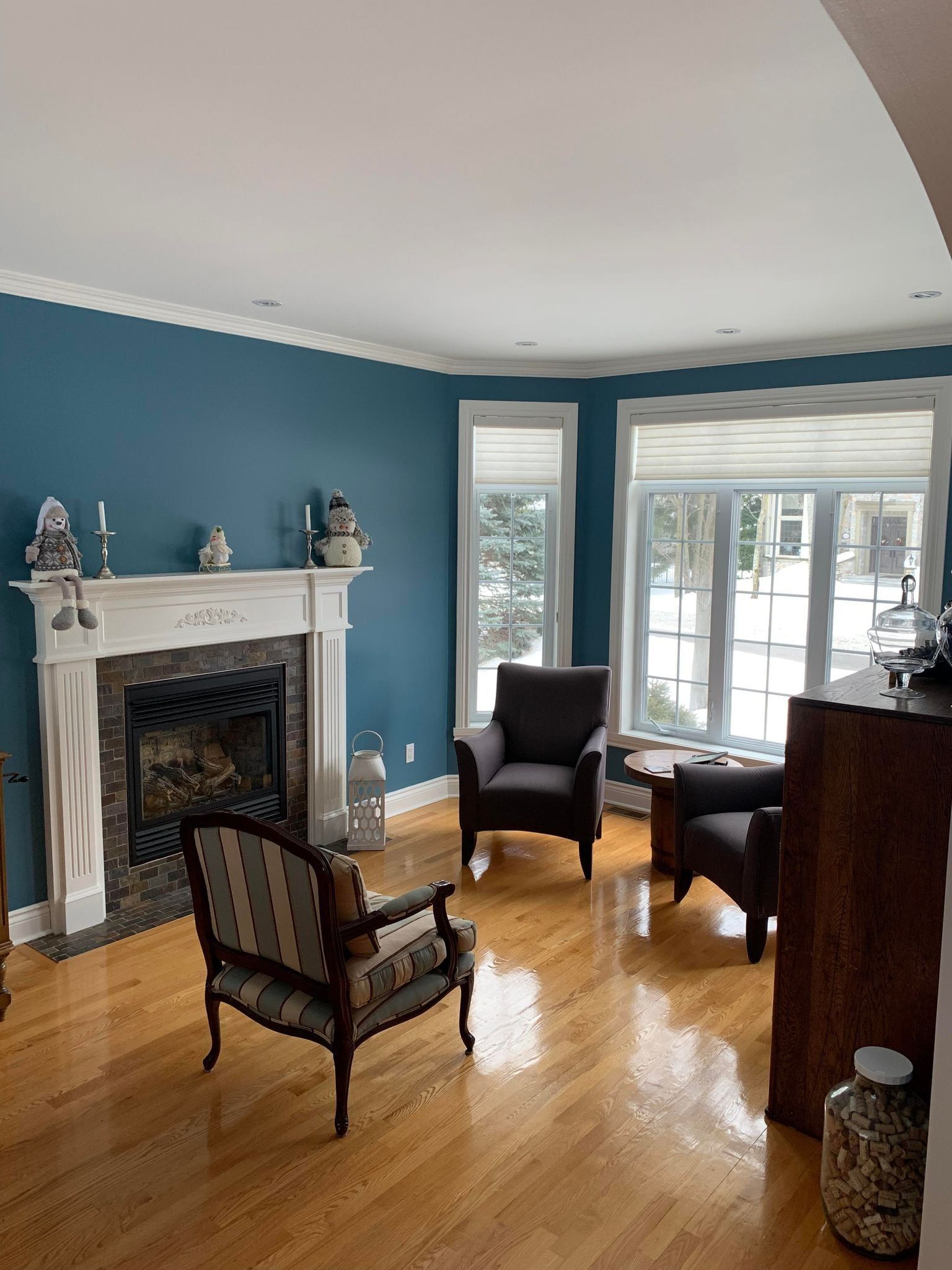 Un salon avec des murs bleus, une cheminée, des chaises et une table.