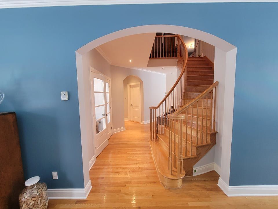 Un couloir avec des murs bleus et un escalier en bois