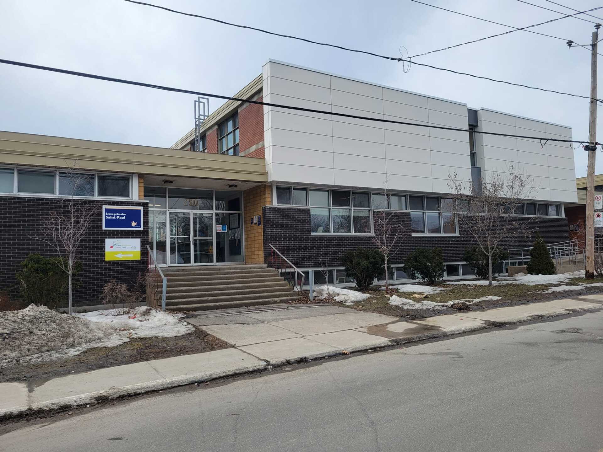 Un grand bâtiment avec des escaliers menant à l'entrée se trouve sur le côté de la route.