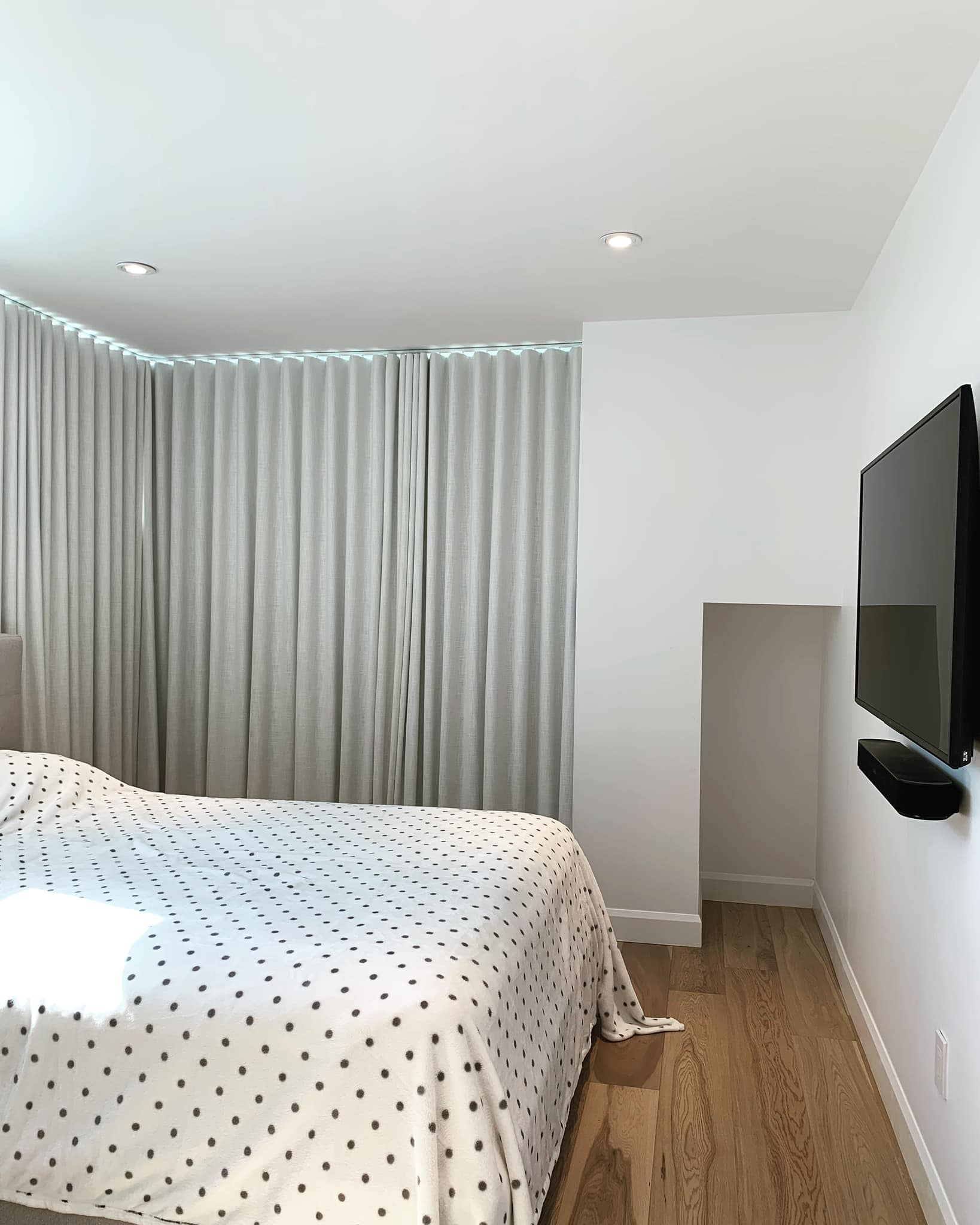 Une chambre avec un lit et une télévision au mur