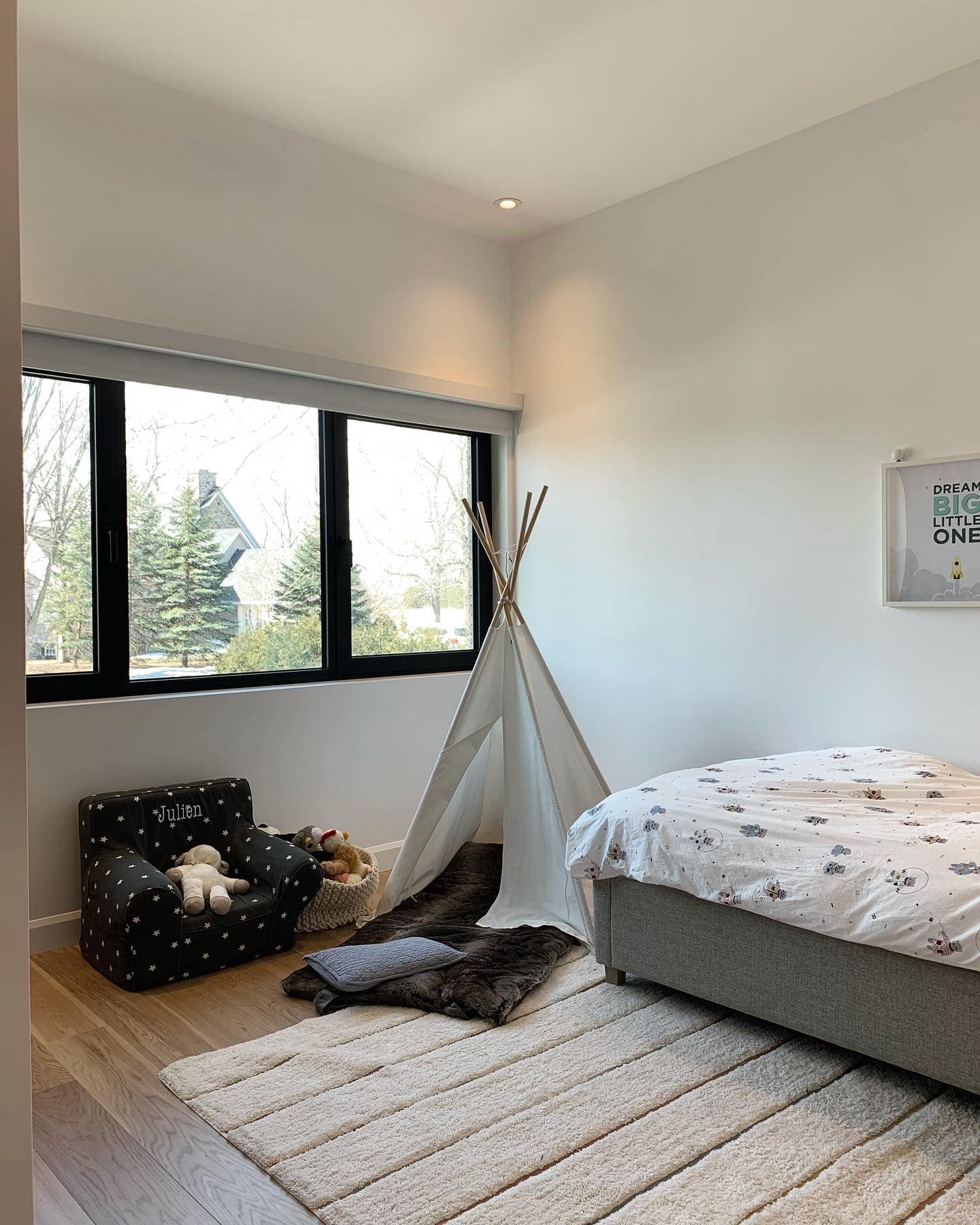 Une chambre avec un lit, une chaise, un tipi et une fenêtre.