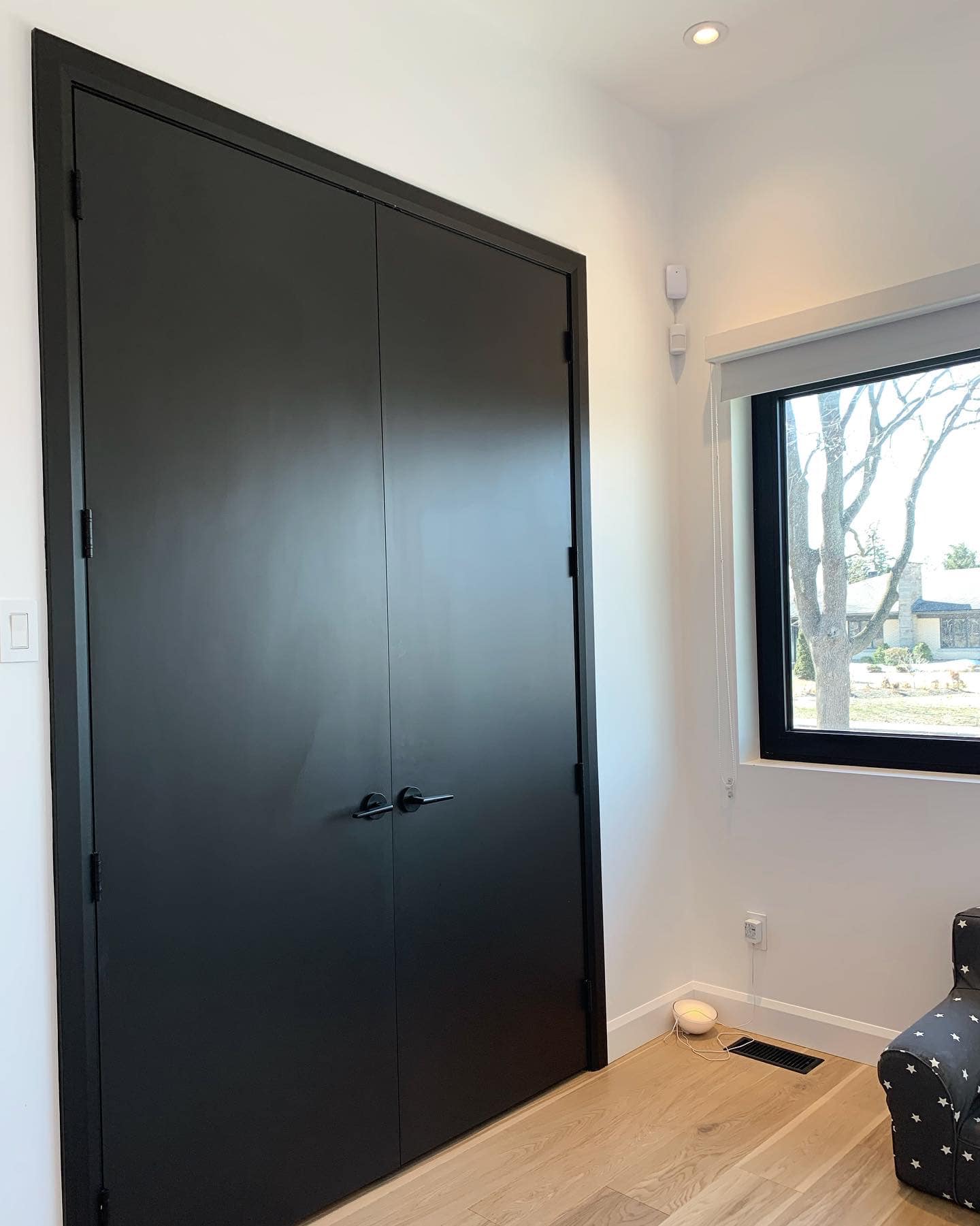 Une porte noire se trouve dans une pièce à côté d'une fenêtre.