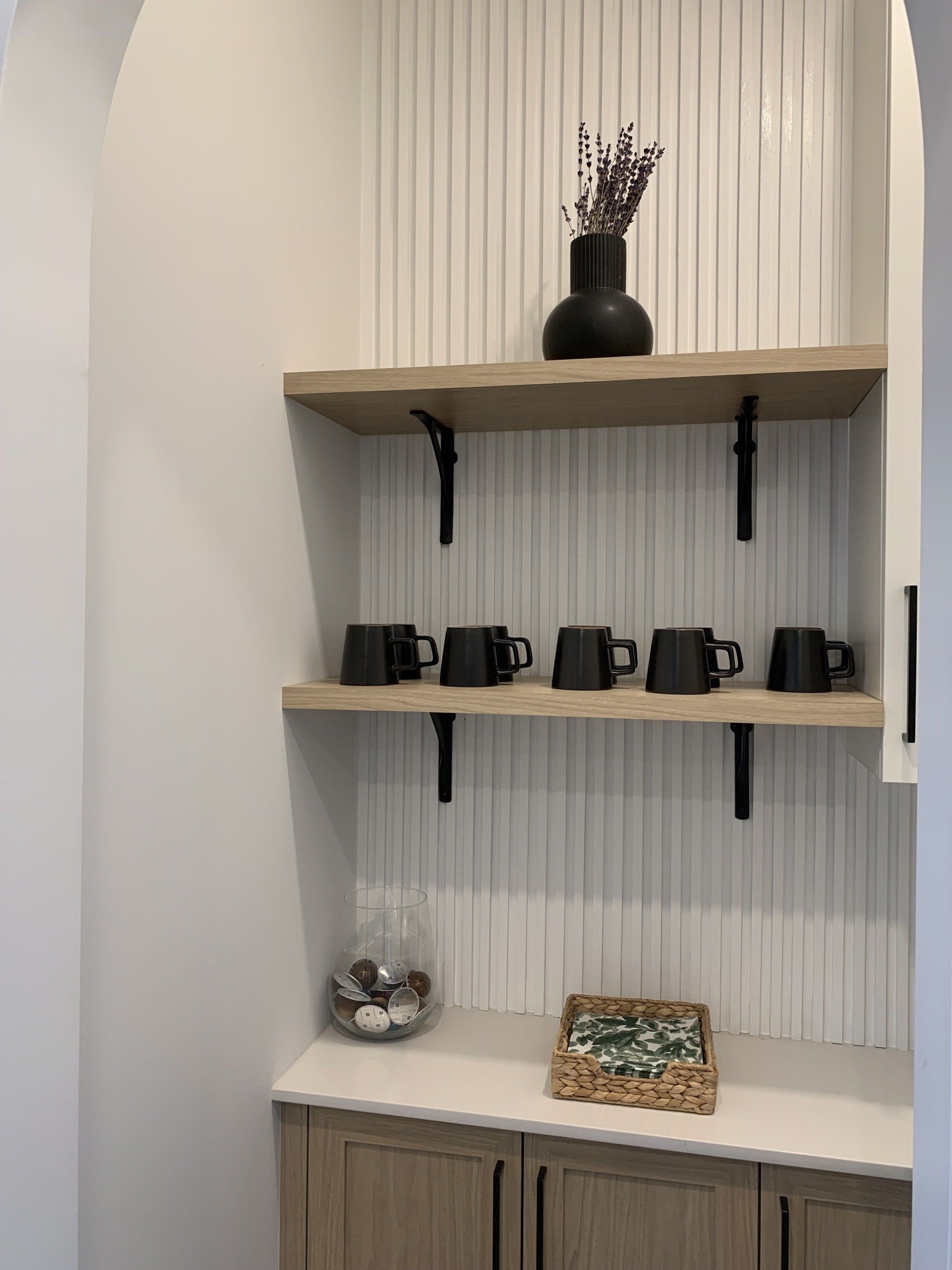 Un garde-manger avec une étagère remplie de tasses et d'un vase.